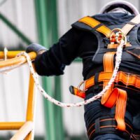 person with safety harness hooked onto railing for fall protection